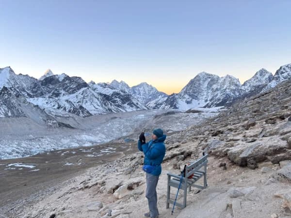 Trekker photographing sunrise panorama from Kala Patthar with Everest Base Camp and Himalayan peaks in background